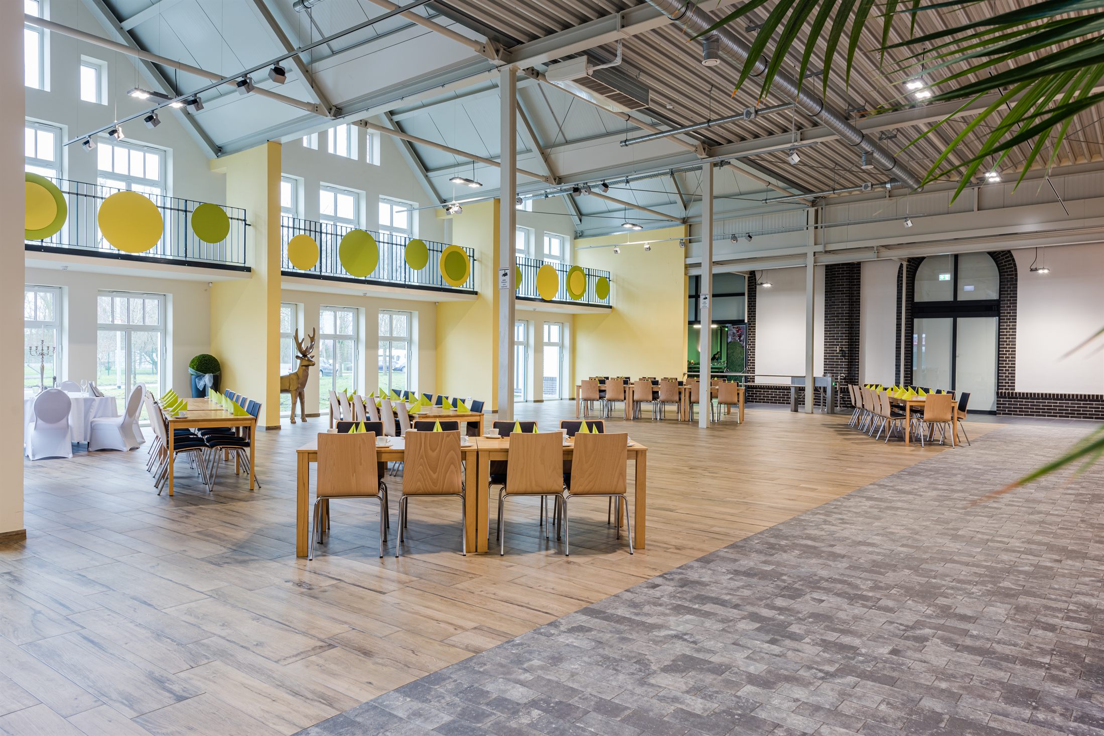 Der große Saal mit langen, festlich eingedeckten Tafeln, Galerie-Ebene und hohen Fenstern